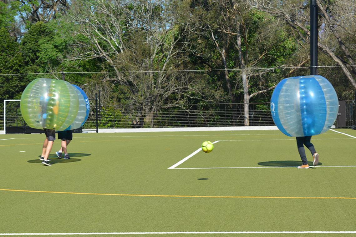 A team of bubble football players bounce off each other on the synthetic playing fields at St Lucia campus.